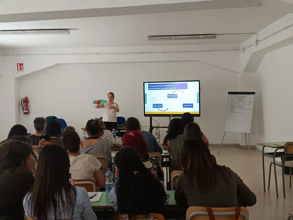Francesca Magostini tiene una lezione in aula di formazione, con una slide sulle trasformazioni sensori-motorie